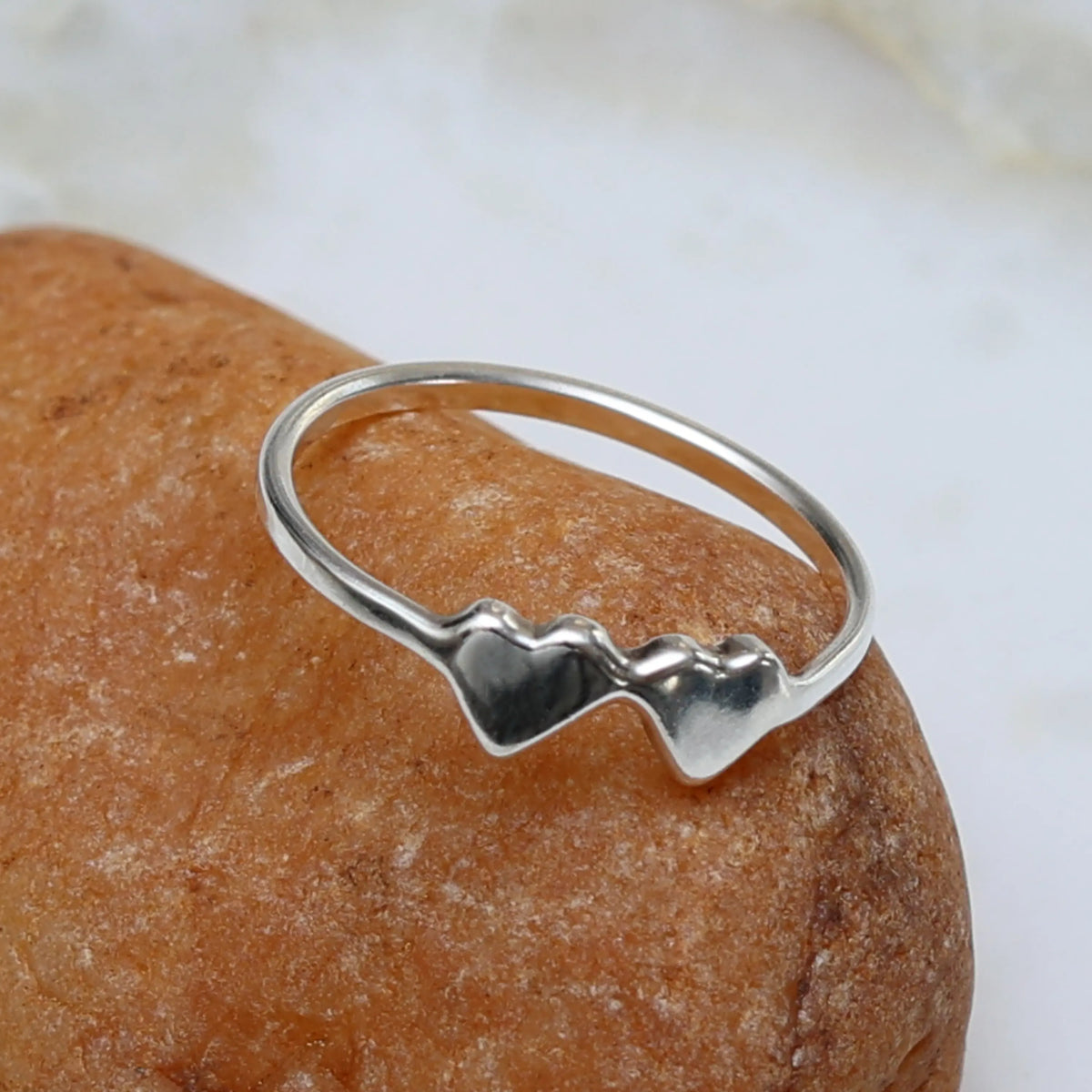 Silver ring with a heart design on a brown rock