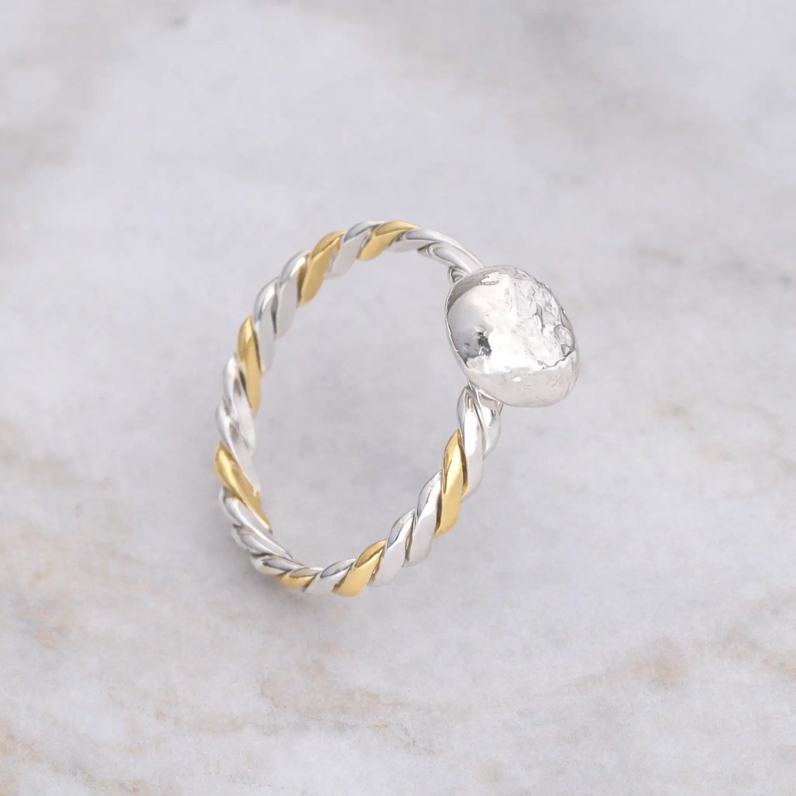 Silver and gold ring on a stone surface